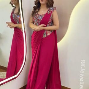 May include: A magenta-colored formal dress with a decorative bodice and draped skirt. The bodice features a colorful floral pattern. The dress is sleeveless and has a flowing, elegant design, suitable for special occasions.