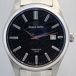 K&ouml;nnte beinhalten: Eine Grand Seiko-Uhr aus Edelstahl mit schwarzem Zifferblatt und silbernen Zeigern. Das Zifferblatt zeigt den Text "Grand Seiko" und "Spring Drive 5 Days". Das Datum wird auf 3 Uhr angezeigt.