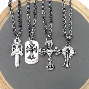 Puede incluir: Cuatro collares de metal plateado con cadenas de eslabones gruesos. Los colgantes incluyen una daga con el texto Chrome Hearts, una placa rectangular con una cruz y el texto Chrome Hearts 925 1998, una cruz ornamentada y un emblema circular.