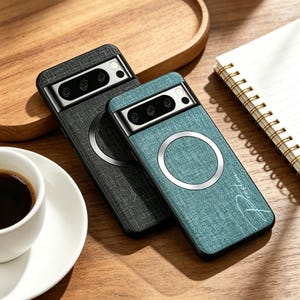 May include: Two smartphone cases with a fabric-like texture, one in dark gray and one in teal. Each case features a black camera module, a circular magnetic charging ring, and the name Preston written in a cursive script on the teal case.