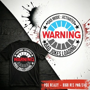 Op de afbeelding: Een zwart t-shirt met een cirkelvormige afbeelding met de tekst DAD MODE: ACTIVATED, WARNING en BAD JOKES LOADING. Het ontwerp bevat een voortgangsbalk met blauwe en grijze segmenten, sterren en een opvallend rood waarschuwingslabel.