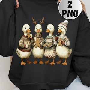 May include: Black sweatshirt with a festive design of four ducks in winter clothes. The ducks are depicted with gingerbread cookies, wearing a sweater, scarf, apron, and hat. The image includes a "2 PNG" graphic.