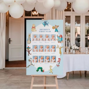 May include: A vertical rectangular sign with a light blue and white striped border featuring the text BRYSON'S FIRST YEAR. The center displays twelve individual photographs of a baby arranged in a grid, surrounded by various colorful storybook character illustrations.