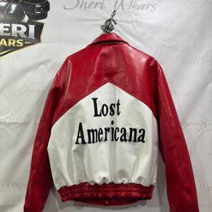 May include: A white ceramic mug with a black handle and the text "But First, Coffee" in a black, handwritten-style font. The mug is on a white surface.