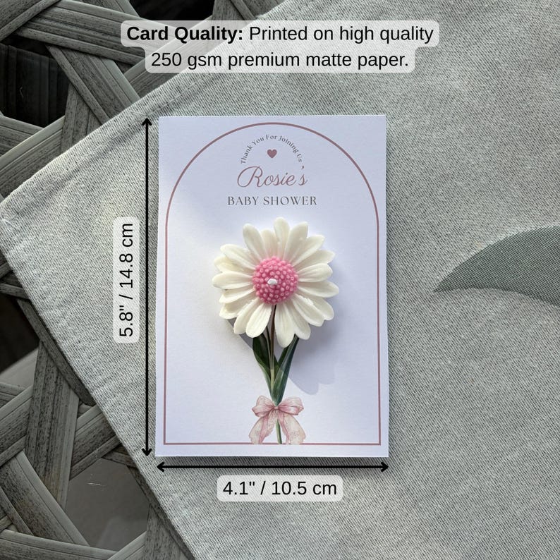 May include: A white card with a pink daisy embellishment, measuring 14.8 cm by 10.5 cm. The card reads "Rosie's BABY SHOWER" and includes the text "Thank You For Joining Us". The card is printed on 250 gsm premium matte paper.