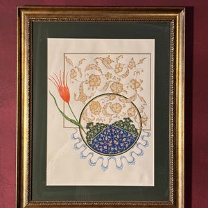 Puede incluir: Obra de arte enmarcada con un marco dorado, que muestra un diseño floral detallado en tonos dorados y beige. Un tulipán naranja está a la izquierda. La obra de arte incluye un patrón circular con elementos florales azules y verdes.