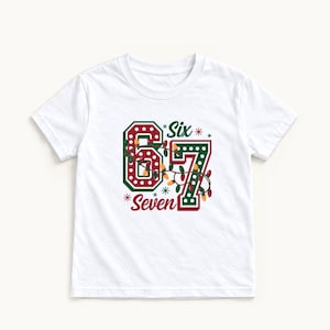 May include: A white short-sleeved t-shirt featuring a graphic of the numbers 6 and 7 in dark green with white polka dots. The design includes a string of colourful Christmas lights wrapped around the numbers, with the text Six and Seven.