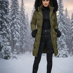 Può includere: Piumino lungo verde oliva con cappuccio e polsini foderati di pelliccia nera. Il cappotto è indossato sopra un dolcevita nero e jeans neri. Lo sfondo mostra una scena di foresta innevata.