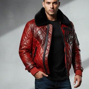 May include: A quilted red leather bomber jacket with a black fur collar. The jacket has a diamond pattern, red cuffs, and a black patch on the left sleeve. The model is wearing a black shirt and blue jeans.