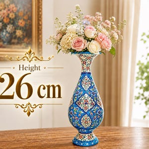 Könnte beinhalten: Eine hohe, schlanke Keramikvase mit ausgestelltem Rand und abgerundetem Boden, verziert mit einem komplexen Blumenmuster in Blau, Weiß und verschiedenen Farben. Die Vase ist 26 cm hoch und mit einem Strauß aus rosa, weißen und cremefarbenen Blumen gefüllt.