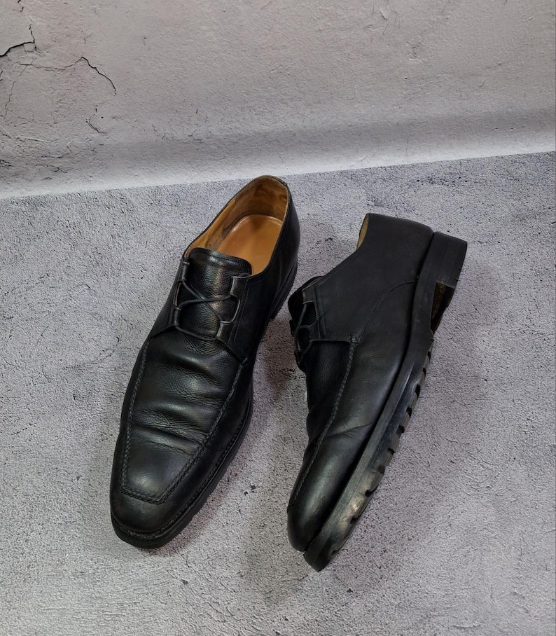 Op de afbeelding: Een paar zwarte leren herenschoenen. De schoenen hebben een klassiek ontwerp met een vetersluiting en een vierkante neus. De zolen zijn zwart en de binnenkant is lichtbruin.