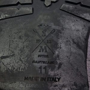 Op de afbeelding: Een witte keramische mok met een zwart handvat en de tekst "But First, Coffee" in een zwarte, handgeschreven lettertype. De mok staat op een wit oppervlak.