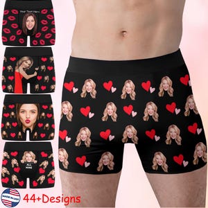 May include: Black boxer shorts with a repeating pattern of faces and red hearts. The shorts have a black waistband and are made in the USA. The image also shows other designs with faces, lips, and the text "Your Text Here" and "All Mine".