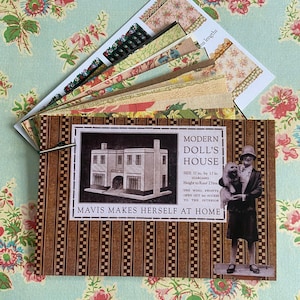 Puede incluir: Un kit de casa de muñecas de estilo vintage con una cubierta a rayas marrones y blancas. Presenta una ilustración en blanco y negro de una casa y el texto "MODERN DOLL'S HOUSE". Incluye muestras de papel estampado. También es visible el texto "MAVIS MAKES HERSELF AT HOME".