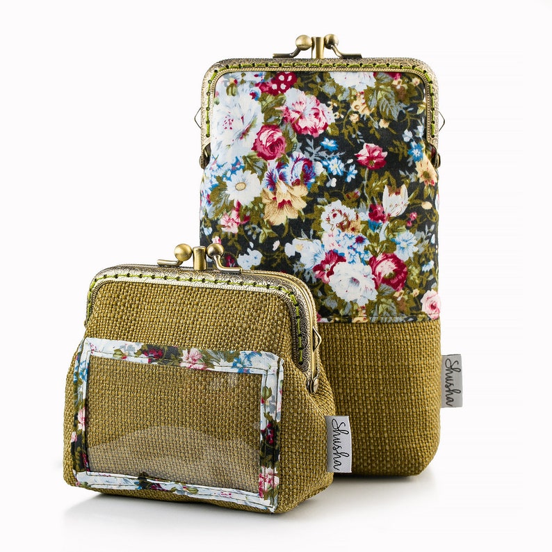 May include: Two gold-toned coin purses with a floral print and a clear plastic window. The larger purse has a black background with pink, white, and blue flowers. The smaller purse has a brown background with a clear plastic window and the word "Shusha" printed on the front.