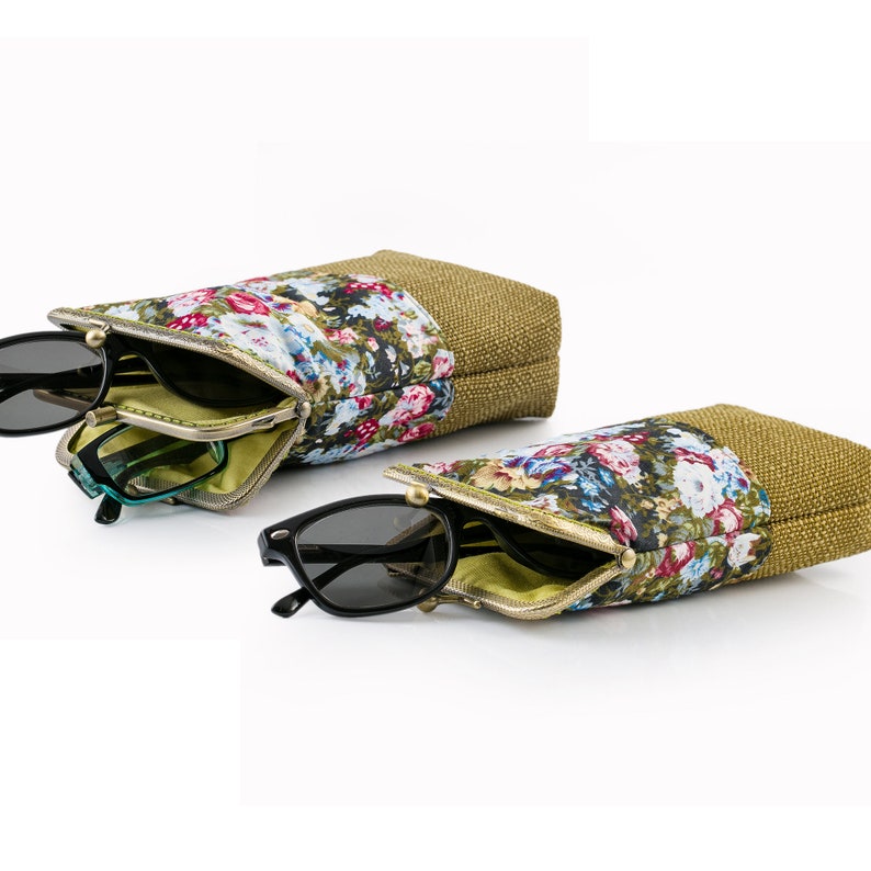 May include: Two floral patterned eyeglass cases with gold metal clasps. The cases are made of a brown fabric with a floral pattern and a gold metal clasp. The cases are open and show the interior lining, which is a light green color. The cases are on a white background.