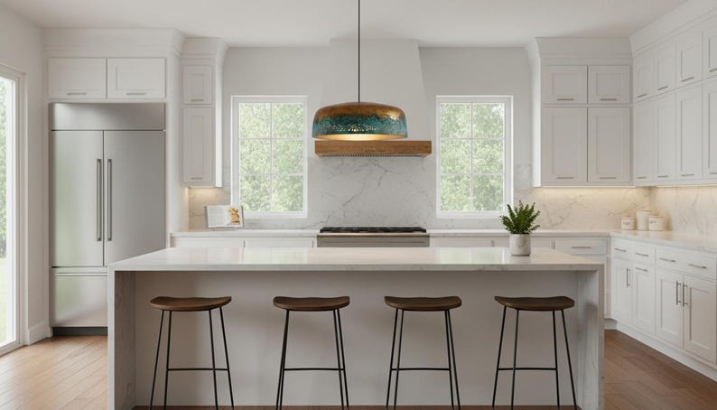 May include: A modern kitchen with white cabinetry, a stainless steel refrigerator, and a large island with four wooden stools. A pendant light with a blue and gold finish hangs above the island. Windows provide natural light.