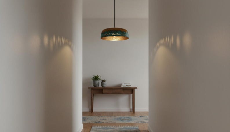 May include: A hallway with a pendant light fixture and a wooden console table. The light fixture has a copper-colored exterior and a gold interior. The console table has two potted plants and a stack of books.