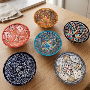 Peut inclure: Six bols décoratifs en céramique avec des motifs floraux et géométriques complexes. Les bols présentent une variété de couleurs, dont le rouge, le bleu, l'orange et le noir, avec des motifs détaillés à l'intérieur et à l'extérieur.
