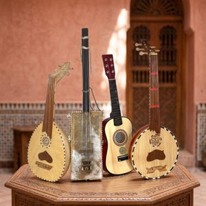 Puede incluir: Cuatro instrumentos musicales de cuerda dispuestos juntos. Dos son laúdes de cuerpo redondo de madera clara, uno es un instrumento rectangular en forma de caja con mástil oscuro y otro es una pequeña guitarra acústica de cuerpo claro.