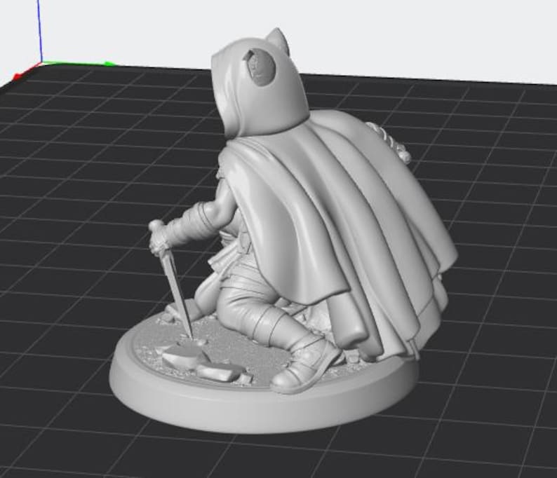 May include: A light grey 3D rendered miniature figure of a hooded character in a cloak, kneeling on a circular base. The figure holds a dagger pointed towards the ground, with visible folds in the fabric of the cloak and detailed leg armour.