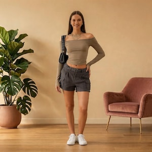 May include: A woman wearing a taupe off-the-shoulder long-sleeve top and gray cargo shorts with a belt. She is also wearing white sneakers and carrying a black shoulder bag. The background is a neutral color.