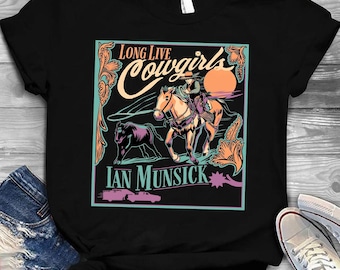 May include: Black t-shirt with a vibrant graphic. The design features the text "Long Live Cowgirls" and "Ian Munsick." It includes a cowgirl riding a horse, a bull, and a sunset.