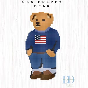 May include: A pixel art style cross stitch pattern of a tan bear wearing a dark blue sweater with a United States flag graphic, blue pants, and brown shoes. The text USA PREPPY BEAR is centered above the bear, and a DD logo is in the bottom right.