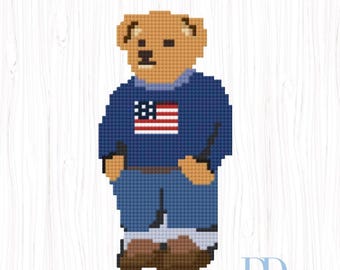 May include: A pixel art style cross stitch pattern of a tan bear wearing a dark blue sweater with a United States flag graphic, blue pants, and brown shoes. The text USA PREPPY BEAR is centered above the bear, and a DD logo is in the bottom right.