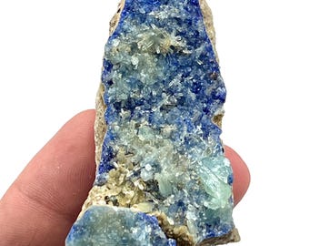 May include: A natural mineral specimen featuring a vibrant blue crystalline structure with lighter blue and clear crystal formations. The mineral is set in a beige matrix, showcasing its natural beauty. This unique piece is ideal for collectors.