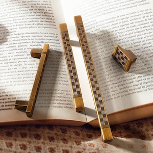 May include: Four wooden desk accessories: three long, rectangular pen holders and a small, square container. The items have a light brown color with a checkered pattern.