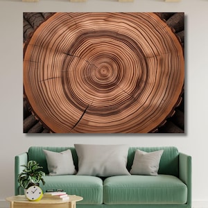May include: A large rectangular canvas print showing a detailed cross-section of a tree trunk. The wood grain has concentric rings in shades of brown and tan, with dark brown accents. The artwork is displayed above a green sofa.