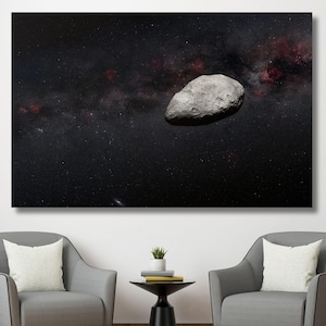 May include: A large canvas print depicting a celestial scene. A gray, asteroid-like object floats in a dark, star-filled sky with a reddish nebula. The print is displayed above two gray armchairs.