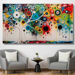 May include: Abstract art canvas print featuring a white tree with colorful circles and paint drips. The artwork has a white background with a colorful border at the bottom. The painting is displayed above two gray armchairs.