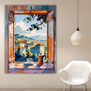 May include: A wall art print depicting an open window frame looking out onto a Mediterranean village with orange-roofed buildings, hills, and a blue sky. On the windowsill sits a white coffee cup on a saucer and a metallic moka pot coffee maker.
