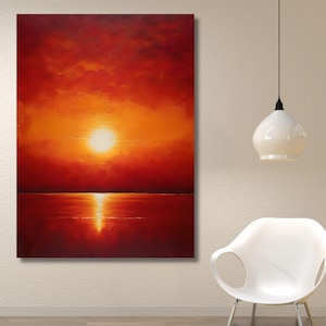 Op de afbeelding: Een rechthoekige wandkunstprint met een levendige zonsondergang boven een kalm wateroppervlak. De scène wordt gedomineerd door diepe tinten rood, oranje en geel, met een heldere zon in het midden van de lucht die reflecteert op het water.