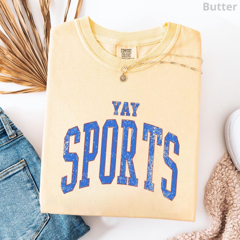 a yellow t-shirt with the text "YAY SPORTS" printed on it, along with a denim jacket and some other clothing items.