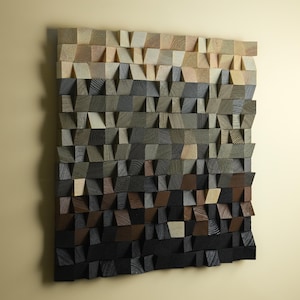 Könnte beinhalten: Holz-Wandkunst mit Farbverlauf. Die Kunst besteht aus kleinen, abgewinkelten Holzblöcken in Beige-, Grau-, Braun- und Schwarztönen. Die Blöcke erzeugen einen strukturierten, dreidimensionalen Effekt, geeignet für die Inneneinrichtung.