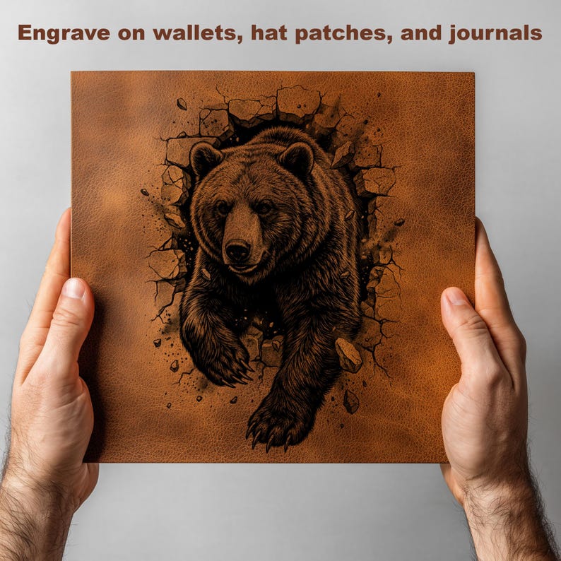 May include: A brown leather-like square with a detailed illustration of a bear breaking through a wall. The text "Engrave on wallets, hat patches, and journals" is at the top. The image is held by two hands.