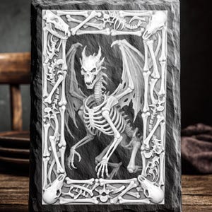 May include: A rectangular, gray slate coaster with a carved, white relief design. The design features a skeletal dragon with wings, framed by bones and skulls. The text "LASER READY PNG" is at the top.