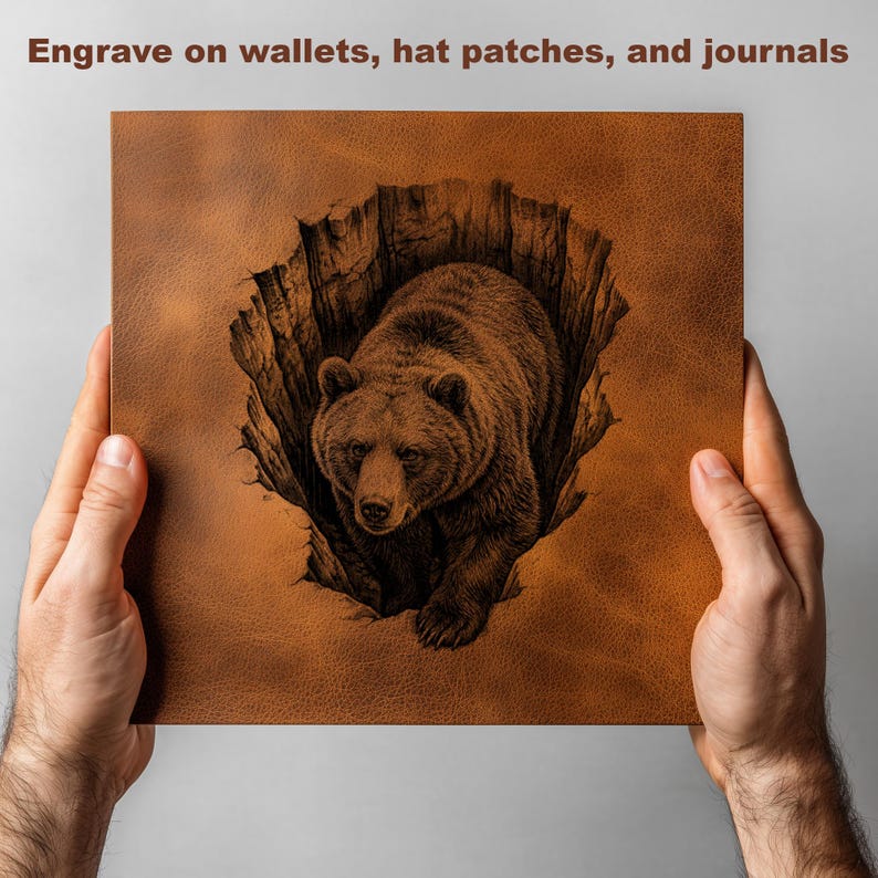 K&ouml;nnte beinhalten: Ein braunes Lederquadrat mit einer detaillierten Gravur eines Grizzlyb&auml;ren, der aus einer Spalte auftaucht. Der Text "Engrave on wallets, hat patches, and journals" steht oben. Das Quadrat wird von zwei H&auml;nden gehalten.