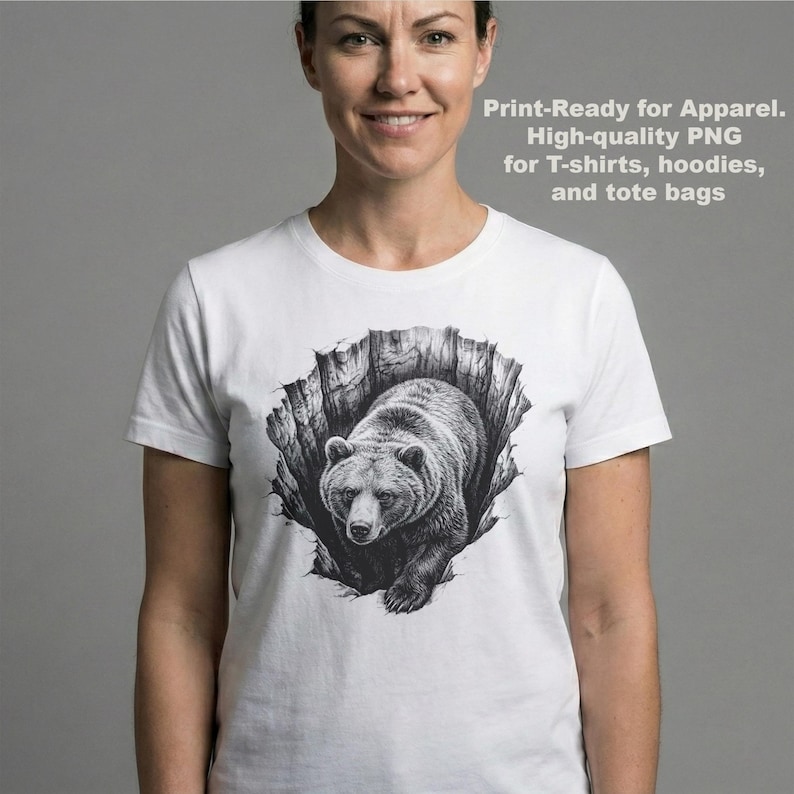 K&ouml;nnte beinhalten: Wei&szlig;es T-Shirt mit einer schwarz-wei&szlig;en Illustration eines B&auml;ren, der aus einer zerfetzten Oberfl&auml;che kommt. Der Text "Print-Ready for Apparel. High-quality PNG for T-shirts, hoodies, and tote bags" ist auf dem T-Shirt aufgedruckt.