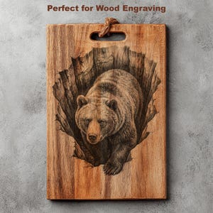 K&ouml;nnte beinhalten: Holzschneidebrett mit detaillierter Gravur eines Braunb&auml;ren, der aus einem ausgeschnitzten Bereich auftaucht. Das Brett hat einen Griff und eine nat&uuml;rliche Holzmaserung. Der Text oben lautet "Perfect for Wood Engraving".