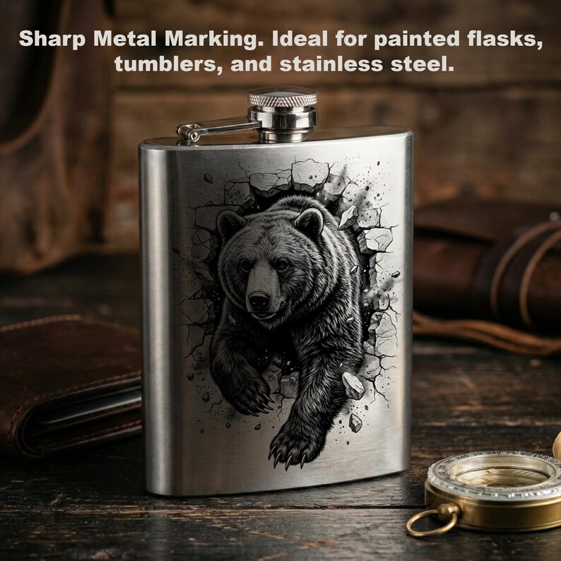 May include: A stainless steel flask with a detailed black and white illustration of a bear breaking through a wall. The flask has a hinged cap and a silver finish. The text "Sharp Metal Marking" is visible.