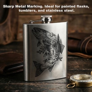 May include: A brushed stainless steel flask featuring a laser-engraved illustration of a large fish. Inside the fish silhouette is a detailed scene of a person fishing in a river surrounded by pine trees and mountains. The flask has a screw-top lid.