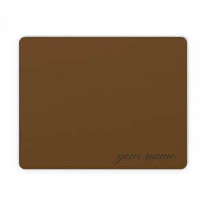 May include: A rectangular brown mouse pad with a textured surface and stitched edges. The text "your name" is printed in a dark, cursive font in the bottom right corner of the mouse pad, providing a personalized touch to the desk accessory.