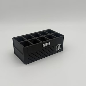 May include: Black rectangular organizer with 12 compartments. The organizer has the text "MP5" and a logo on the side. The front of the organizer has diagonal lines.