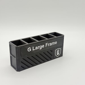 May include: A black rectangular organizer with six compartments. The text "G Large Frame" is printed in white on the front. A logo is on the right side. The organizer has a textured design on the front.