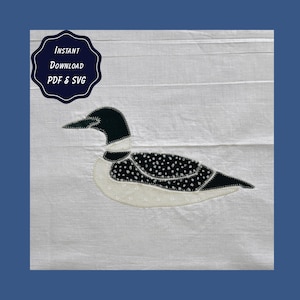 May include: A white fabric background featuring a black and white loon applique with a stitched border. A dark blue scalloped badge in the upper left corner contains the white text: Instant Download PDF & SVG. The loon has a spotted pattern.