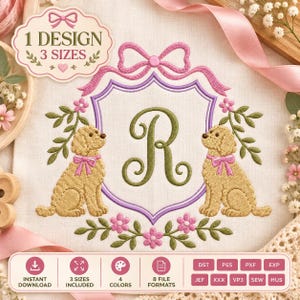 May include: An embroidery design featuring a central letter R in olive green inside a purple shield, flanked by two golden-brown dogs with pink bows. The crest is topped with a pink bow and surrounded by green leaves and pink flowers.